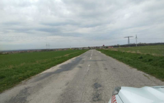 Cesta III/1130 so záplatami a prasklinami vedúca cez polia smerom k hranici s Českom pri Skalici, pred opravou